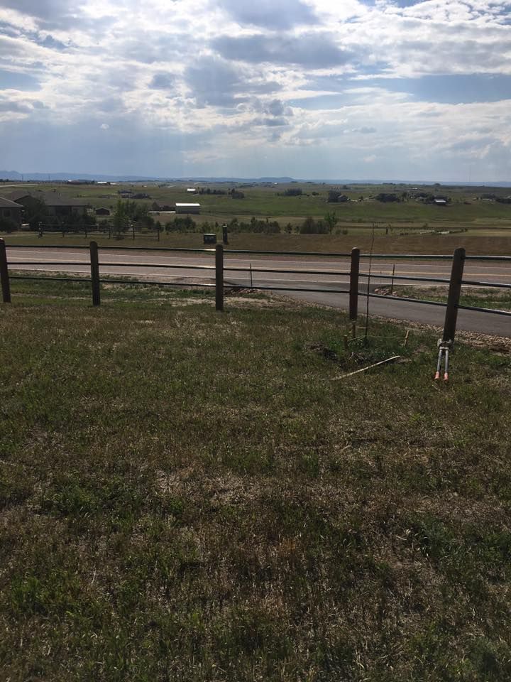 Open field with a wooden fence and cloudy sky over distant hills