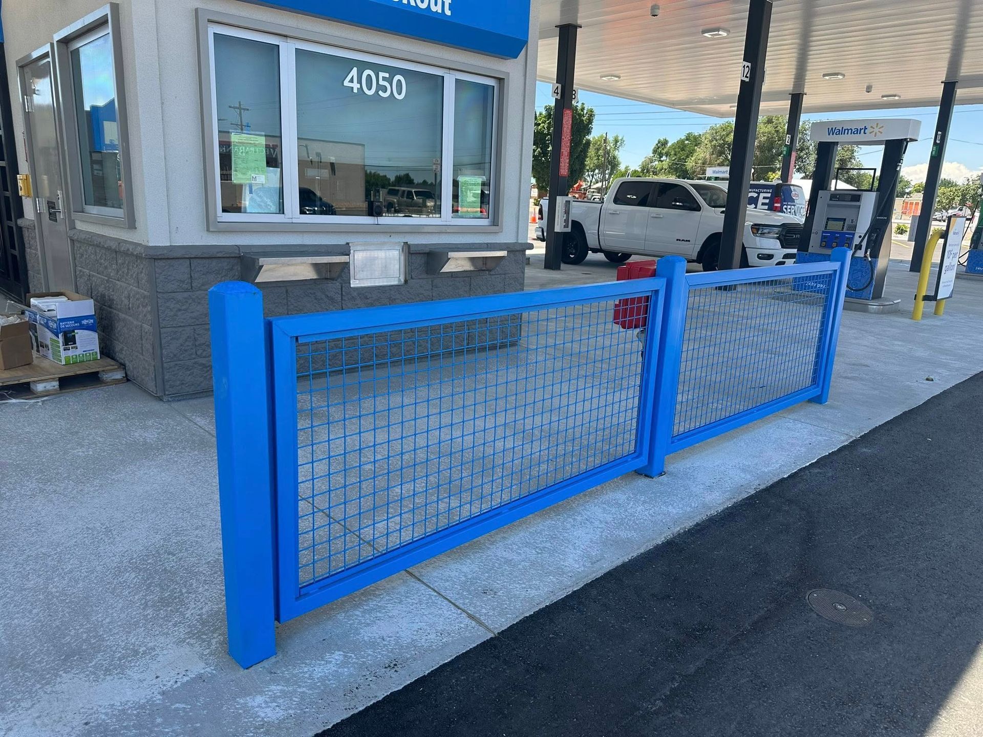 Blue gate blocking a vehicle lane beside a drive-through window and canopy at a gas station