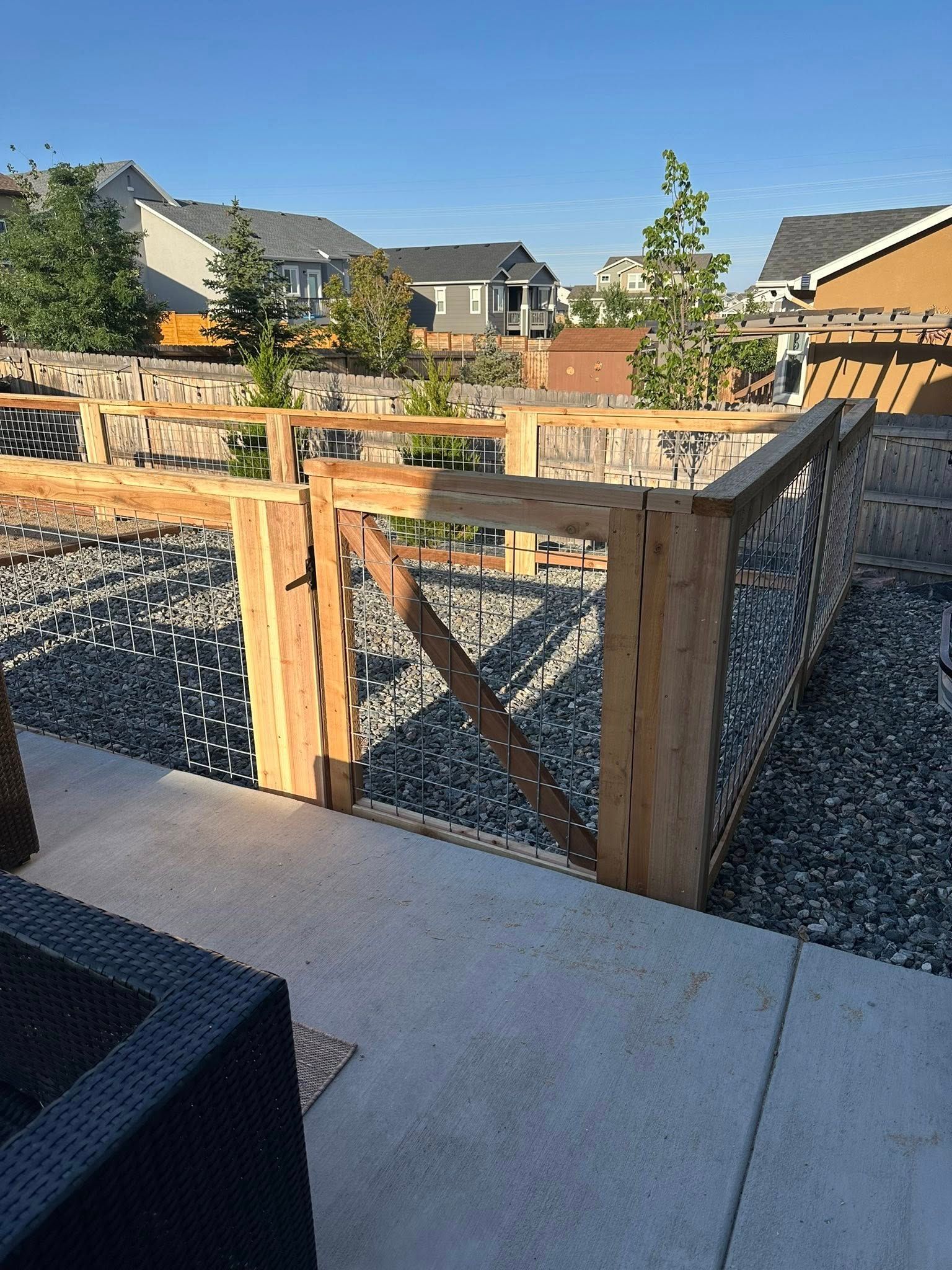 Backyard patio with wooden fence, gravel landscaping, and neighboring houses in the background