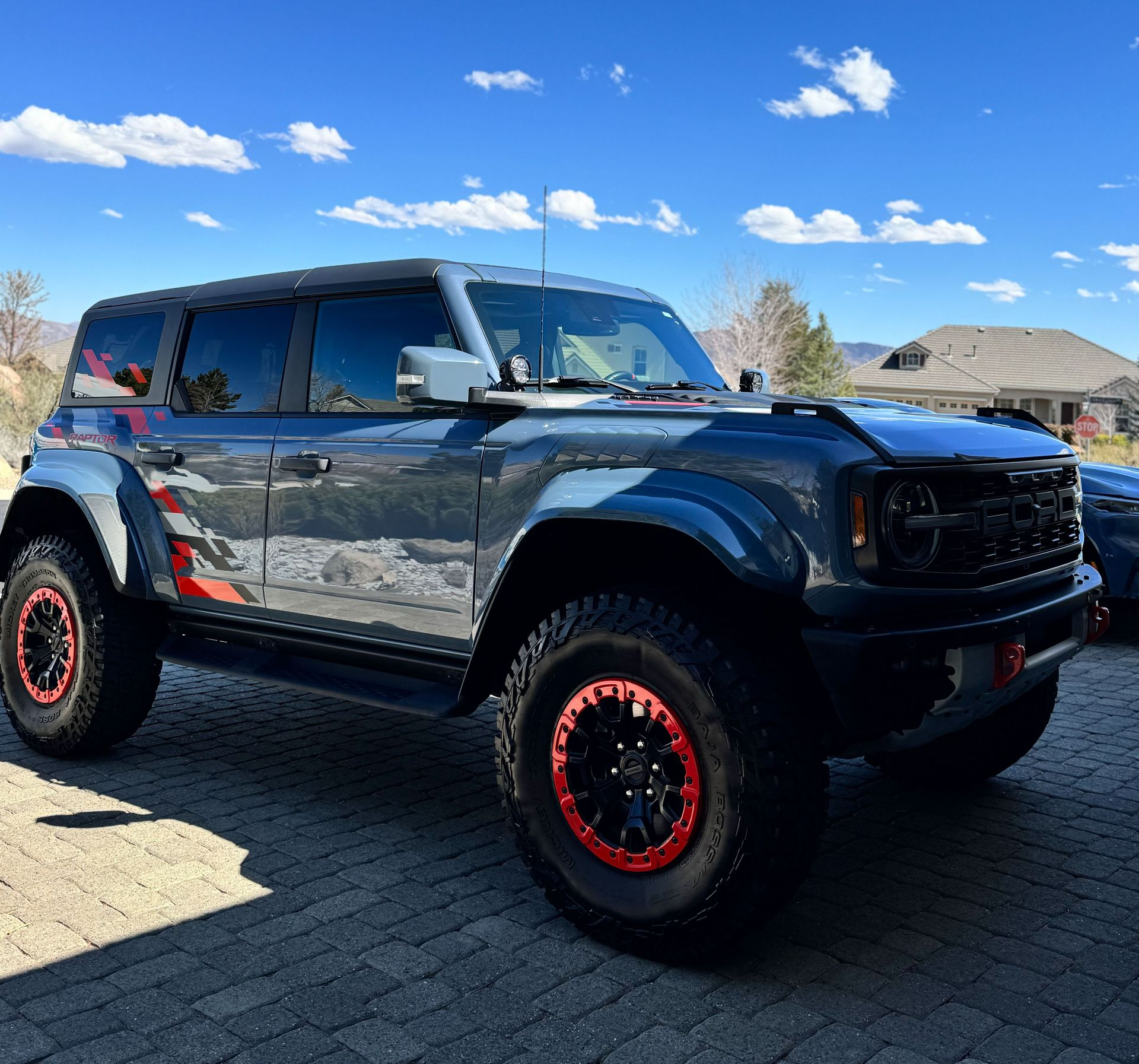 Gray Ford Bronco with red accents parked on a brick driveway on a sunny day.