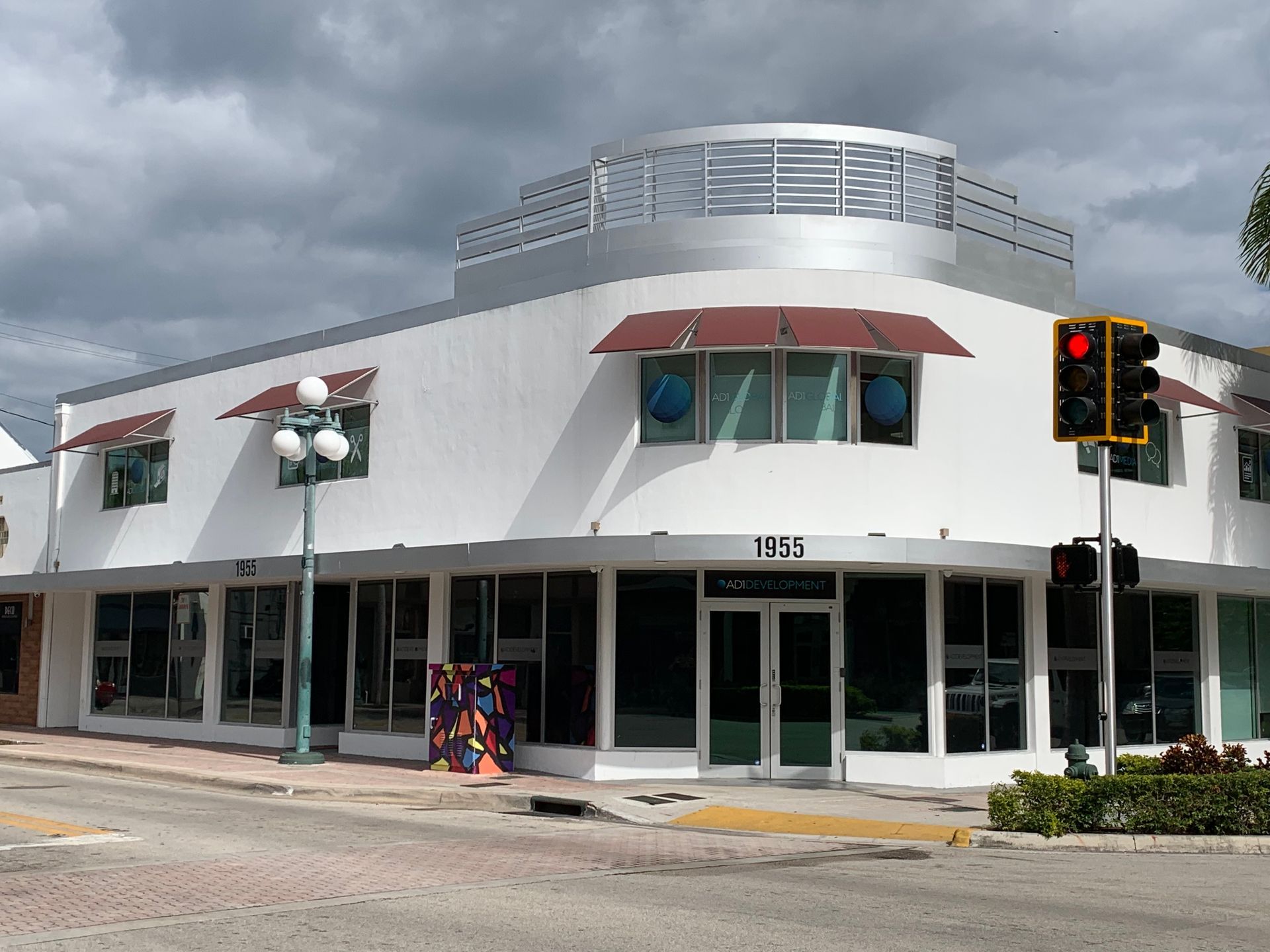 Corner building with white walls, awnings, and large windows. Street corner with a traffic light.