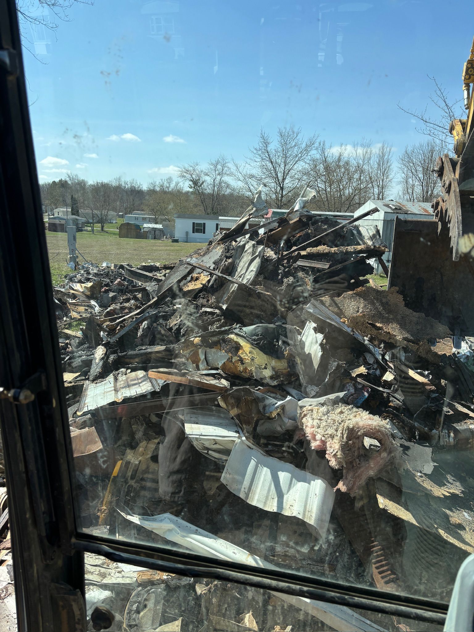 Pile of burned debris outside a window under a clear blue sky