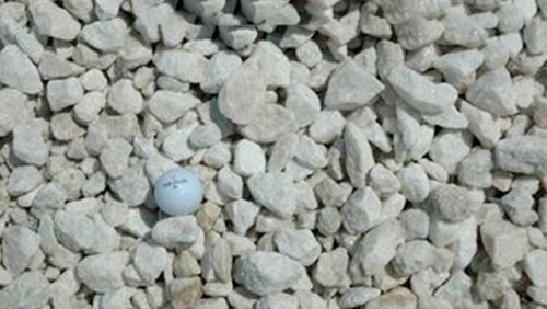 White golf ball on pale gray gravel.
