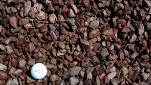 White golf ball on brown gravel stones.