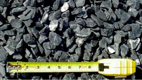 Tape measure laid across a pile of gray crushed stone