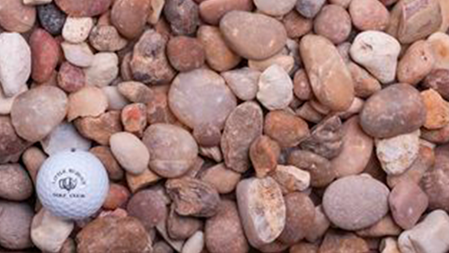 Golf ball among small pink and brown stones