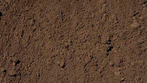 Close-up of rough brown soil or dirt with a granular texture