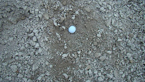 White golf ball on rocky dirt ground
