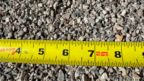 Yellow tape measure on gravel showing 4 to 8 inches