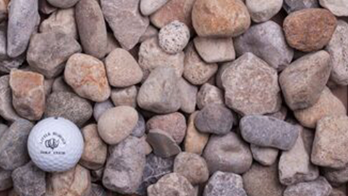 White golf ball among tan and gray pebbles on the ground