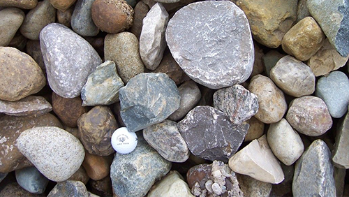 Assorted smooth pebbles in gray, tan, and white, filling the frame.