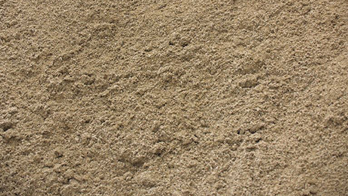 Close-up of tan, sandy soil with a rough, grainy texture