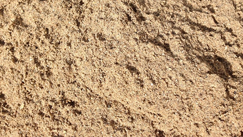 Close-up of light brown sandy soil with a rough, grainy texture