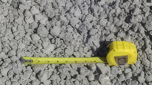 Yellow tape measure lying on gray gravel rocks