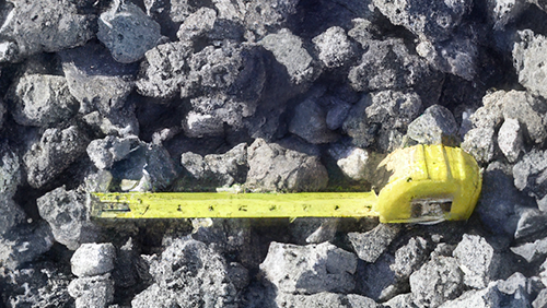 Yellow tape measure lying on rough gray rocks.