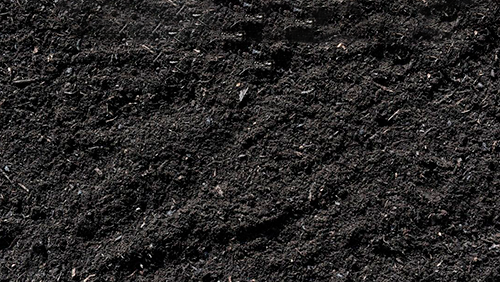 Close-up of dark, rough asphalt or gravel surface with small reflective specks.