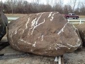 Large brown boulder with white streaks sitting on a trailer outdoors