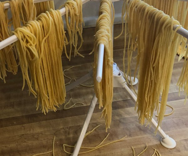 A bunch of noodles are hanging on a drying rack.