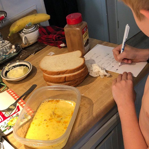 A child is writing on a piece of paper in a kitchen