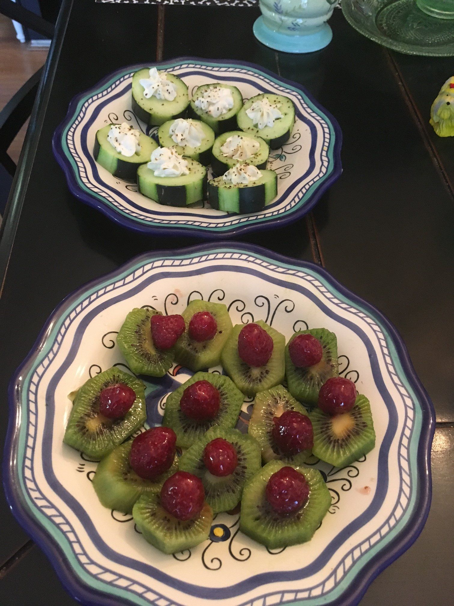 Two plates with kiwi and cherries on them on a table
