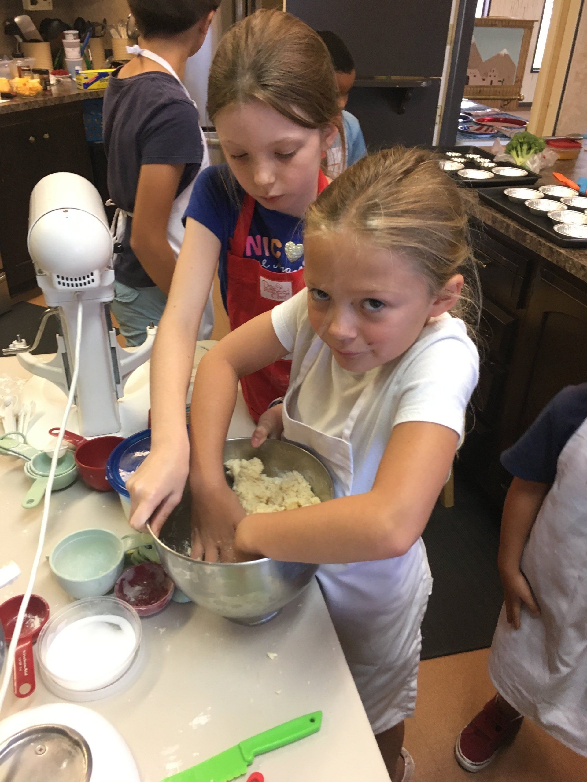 Two young girls are mixing ingredients in a bowl.