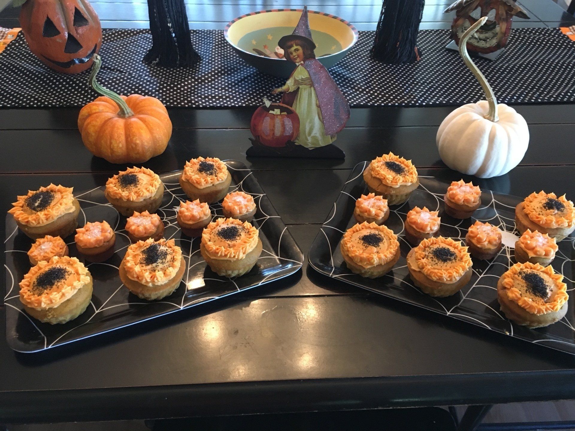Two trays of halloween treats on a table with pumpkins