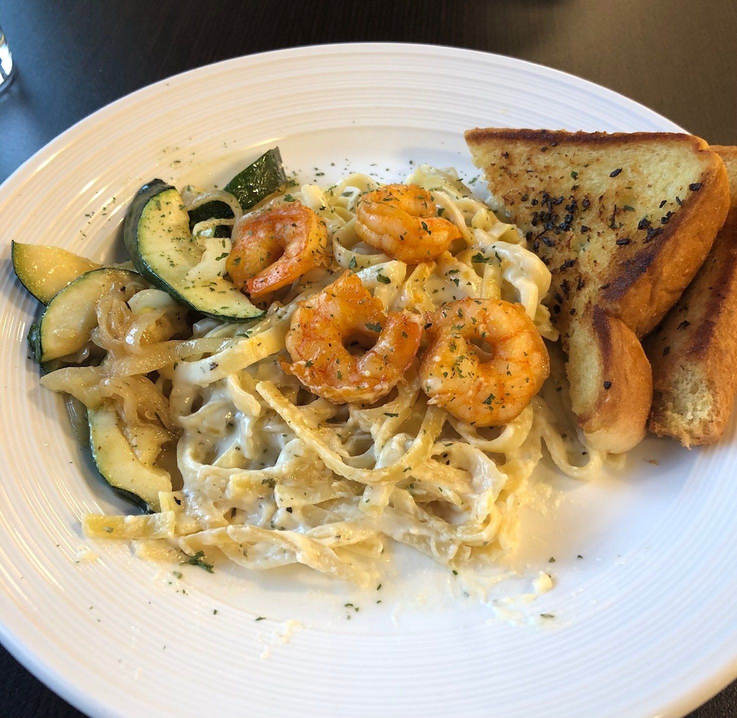 A white plate topped with noodles shrimp and vegetables