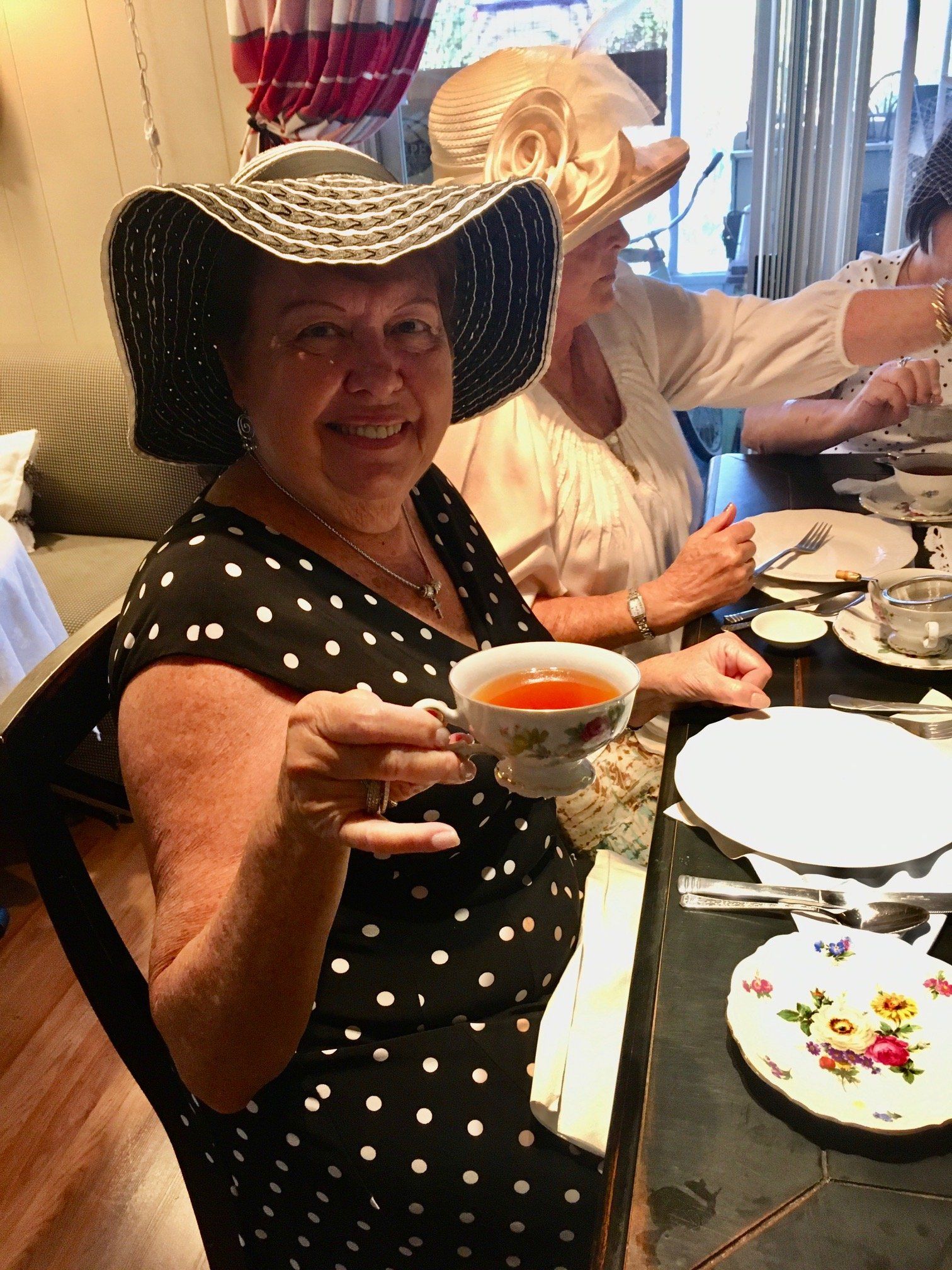 A woman in a hat is holding a cup of tea.