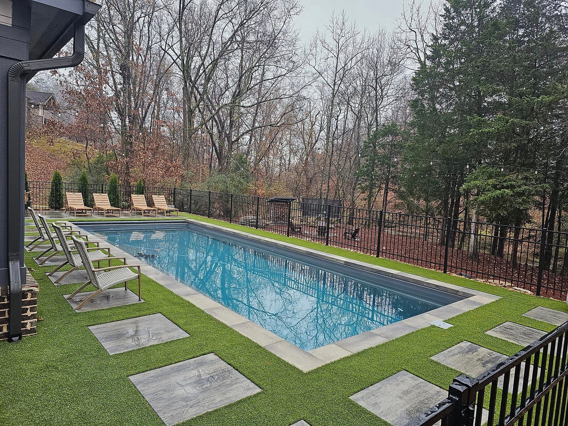 A large swimming pool surrounded by grass and trees in a backyard.