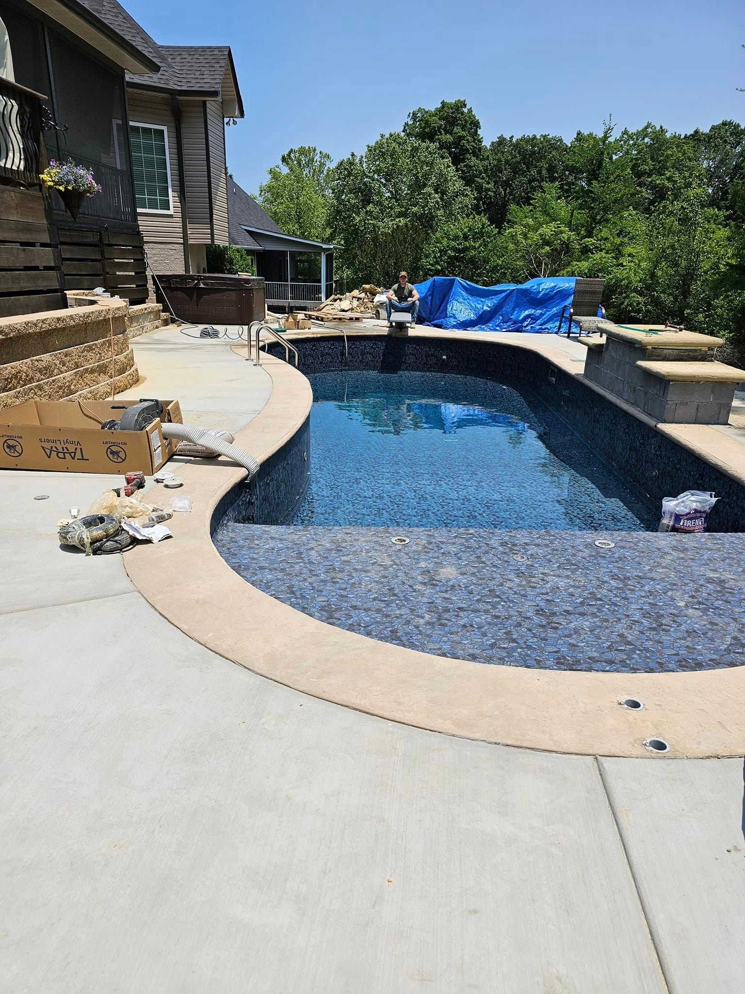 A large swimming pool is being built in the backyard of a house.