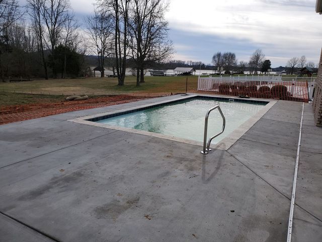 A large swimming pool is surrounded by a concrete patio