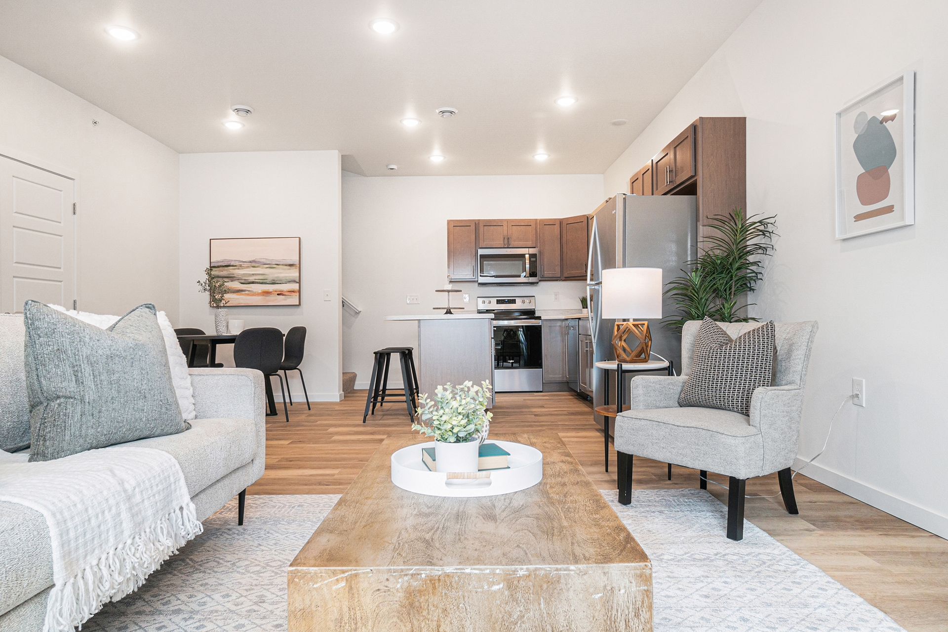 A living room with a couch , chair , coffee table and kitchen.