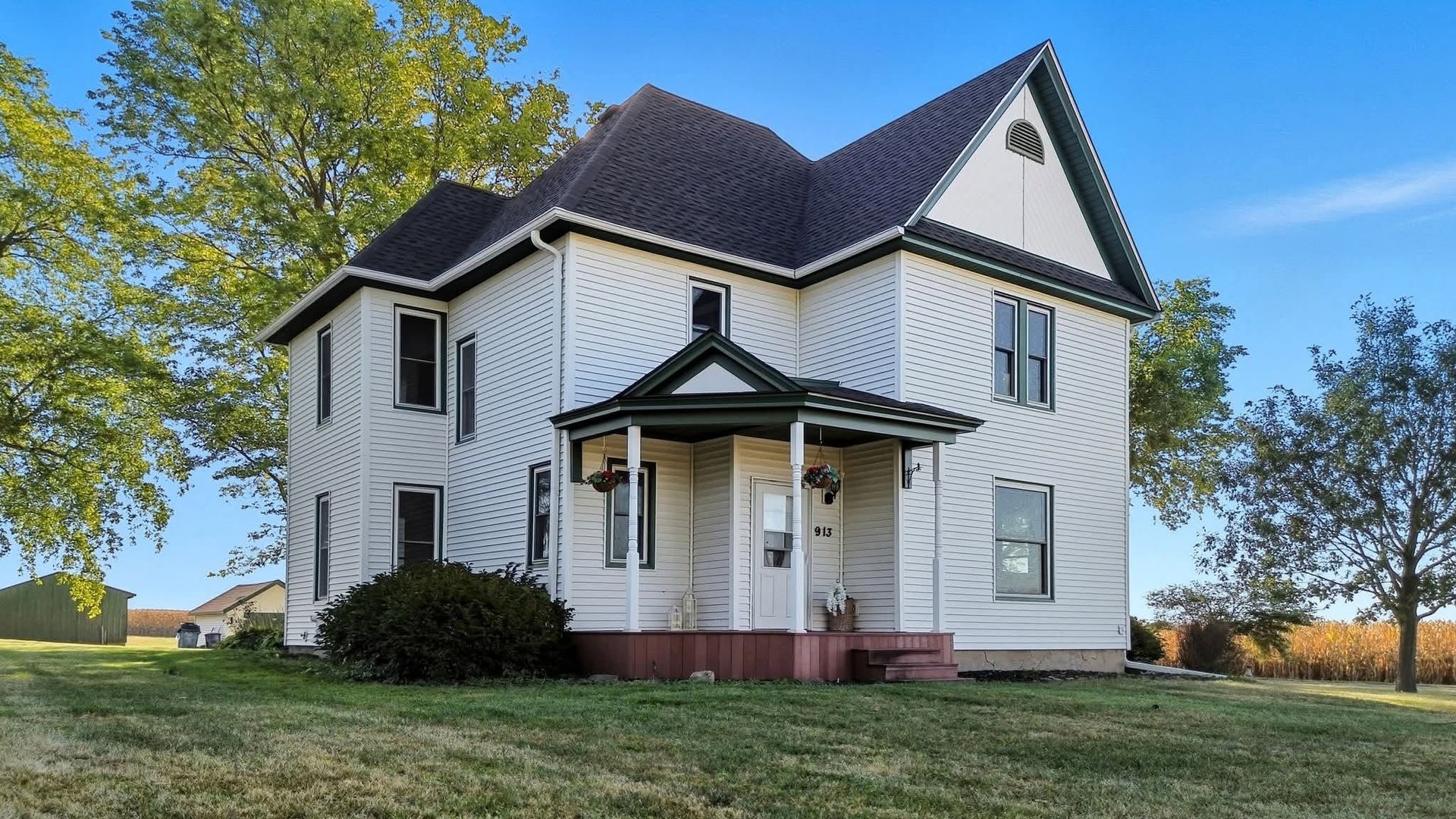 White two-story farmhouse with a covered entrance and green lawn