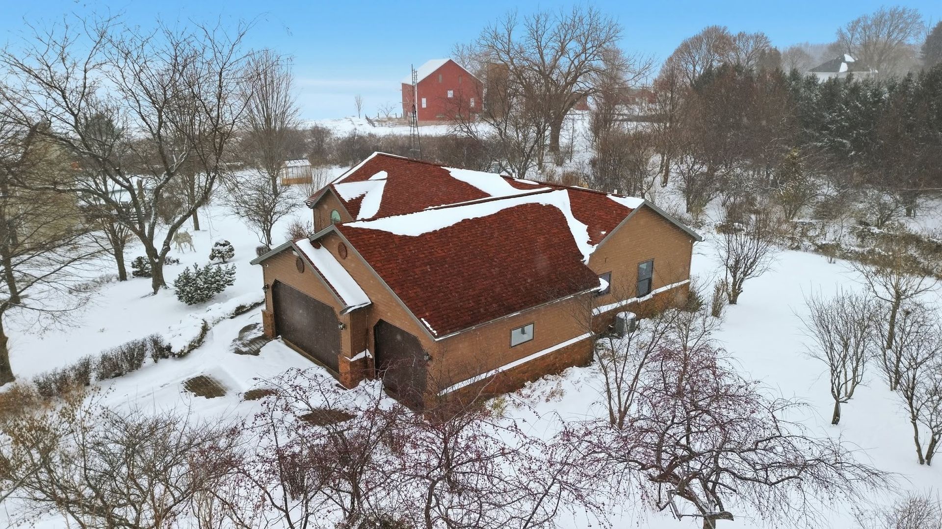 Aerial drone view of a brick home and snowy grounds
