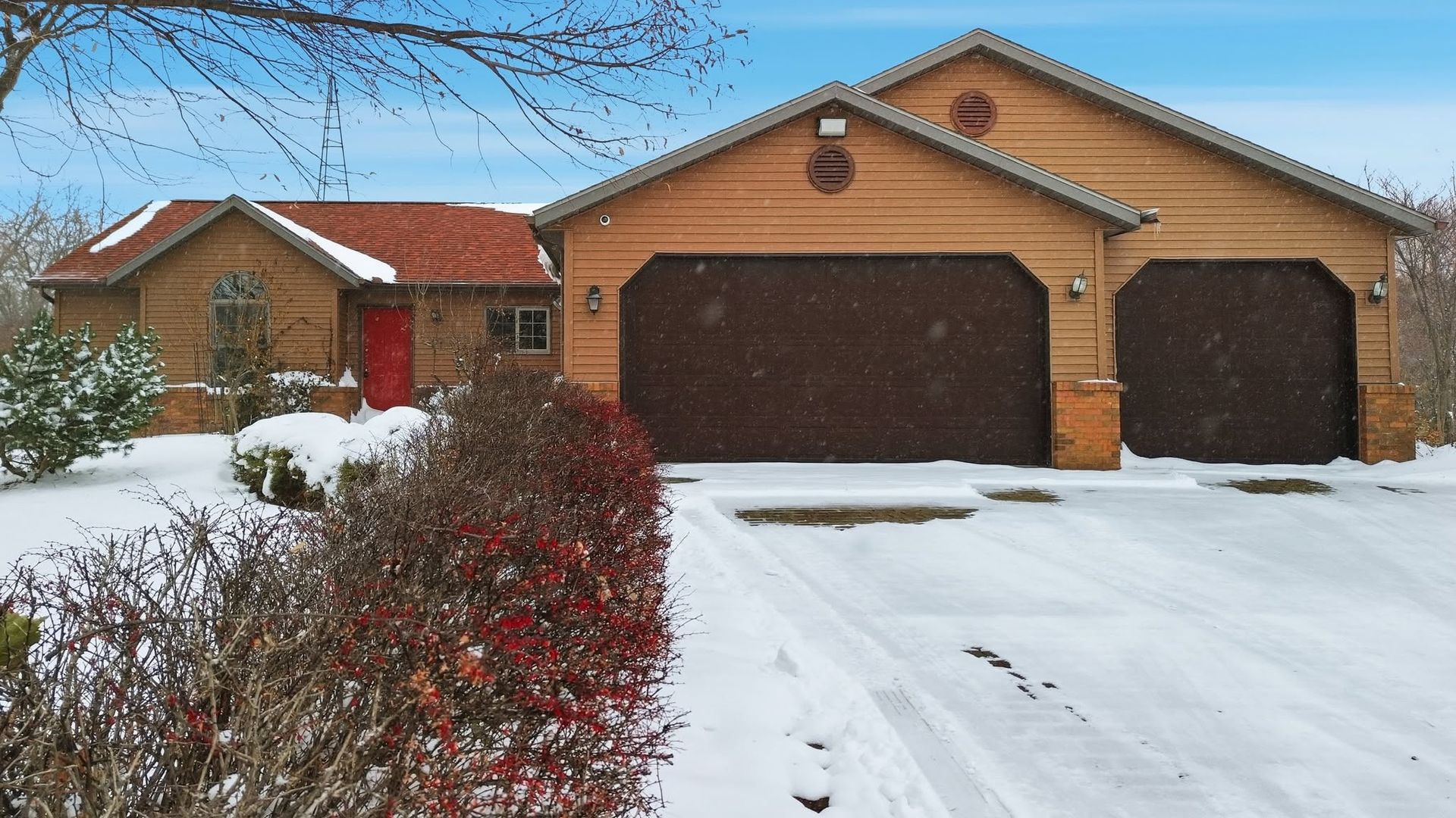Brick home with attached garages and a snow-covered driveway