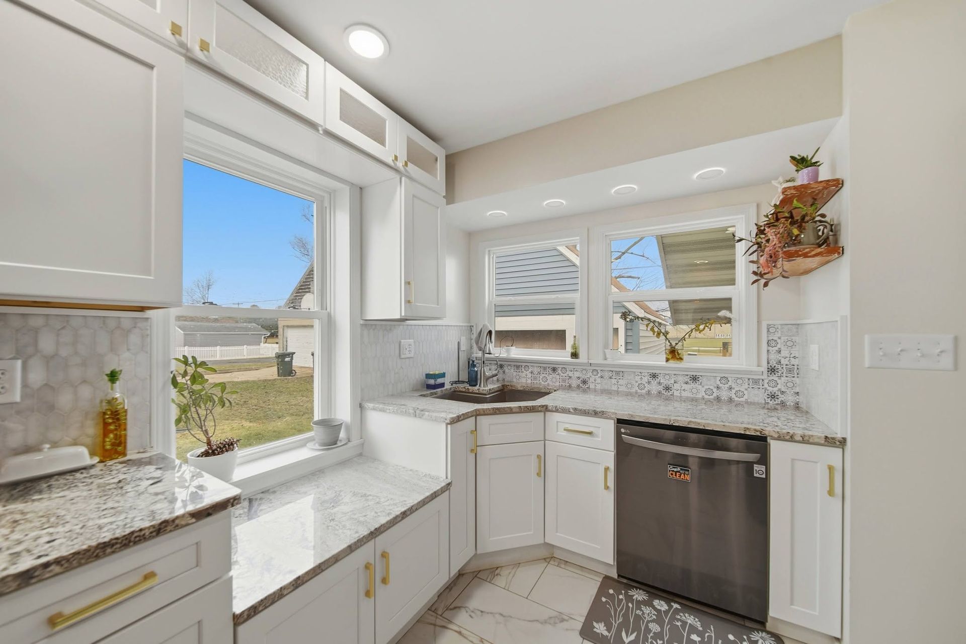 White kitchen corner with granite counters and windows above the sink