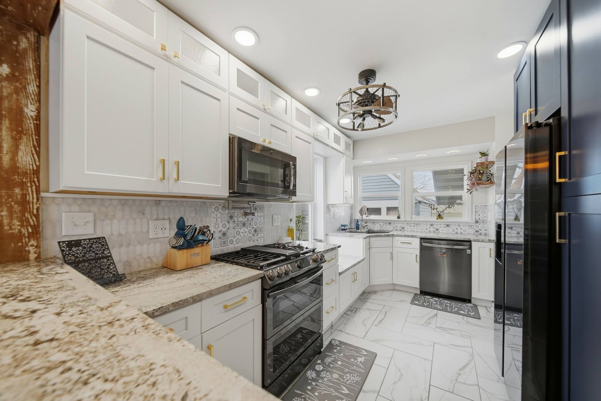 Galley kitchen with white cabinets, granite counters and stainless appliances