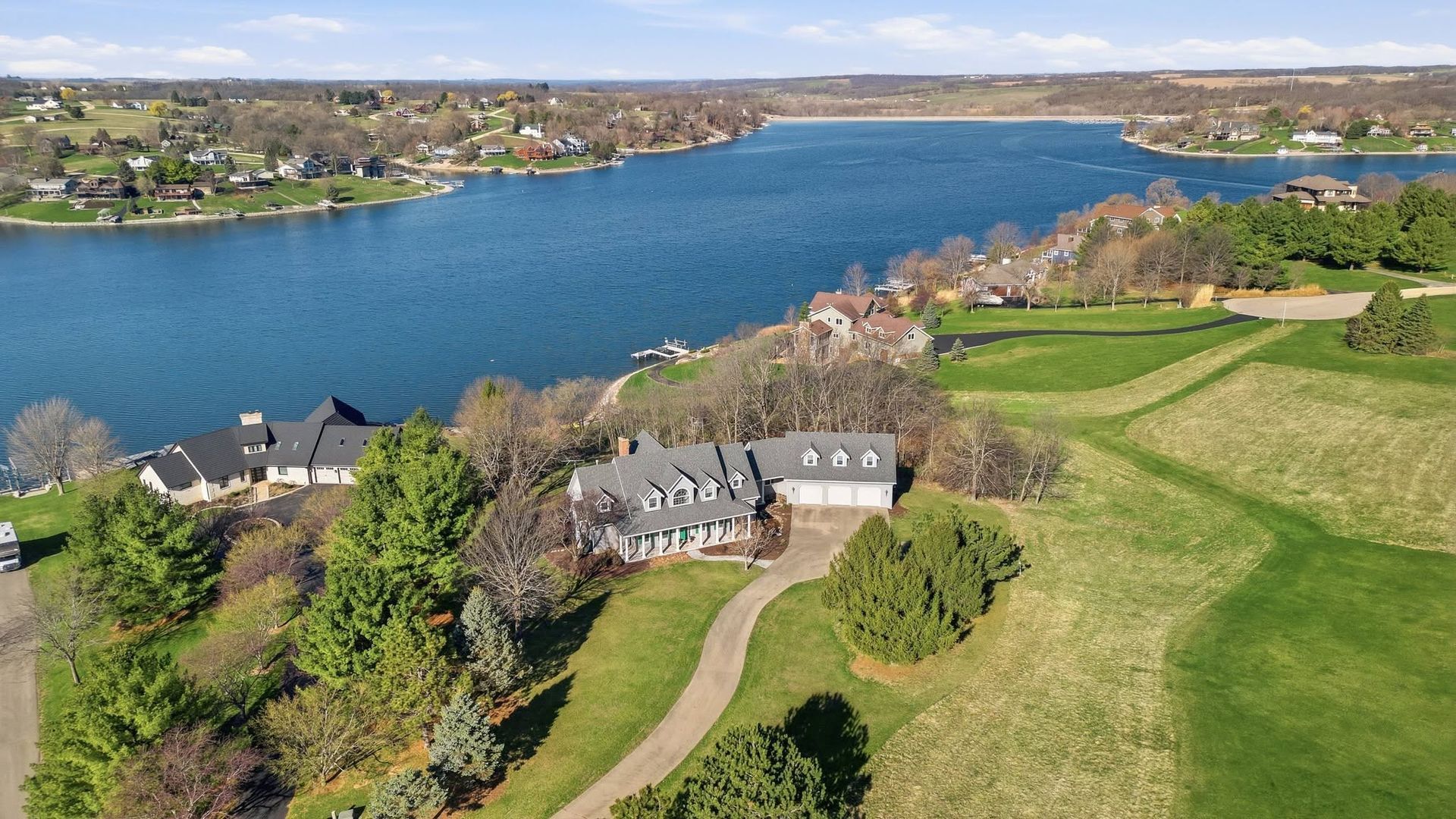 Aerial drone view of a large home and lawn beside a lake