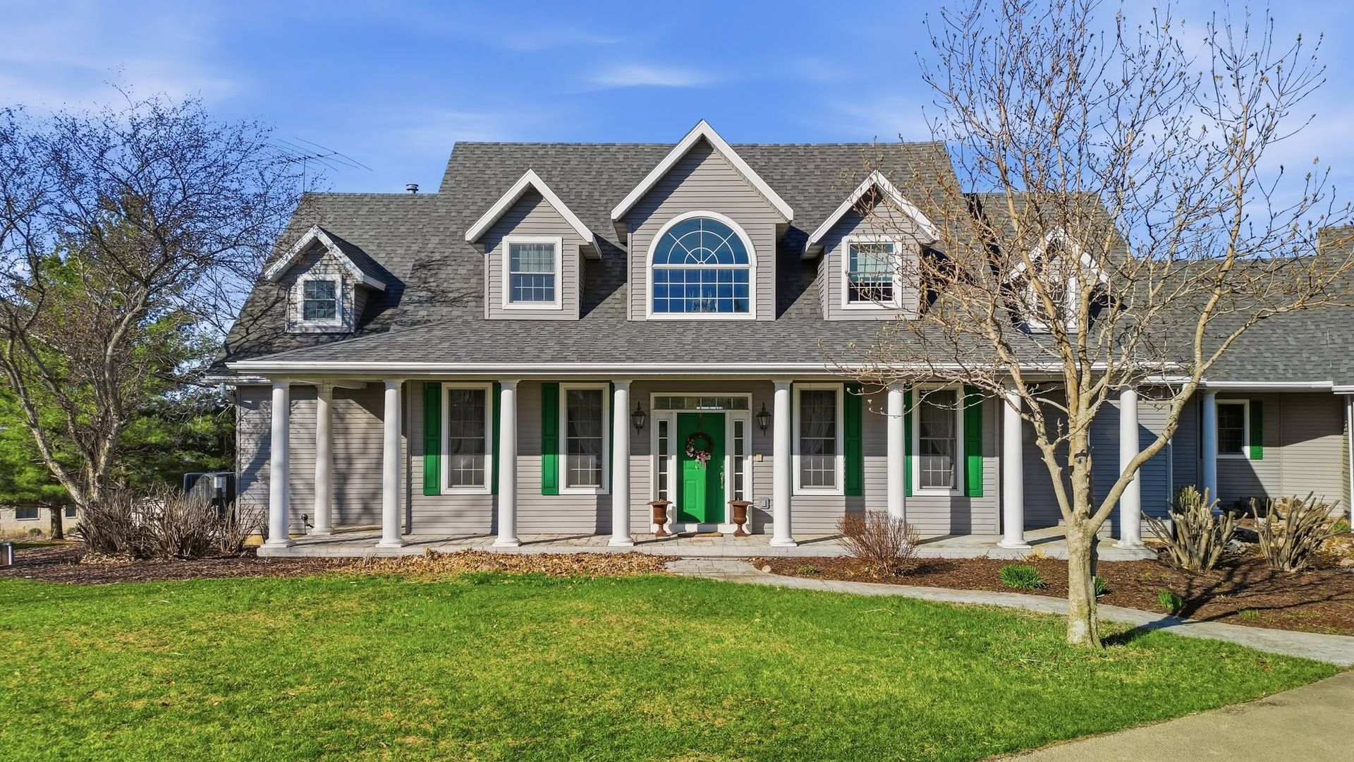 Large home with dormer windows and a long covered front porch