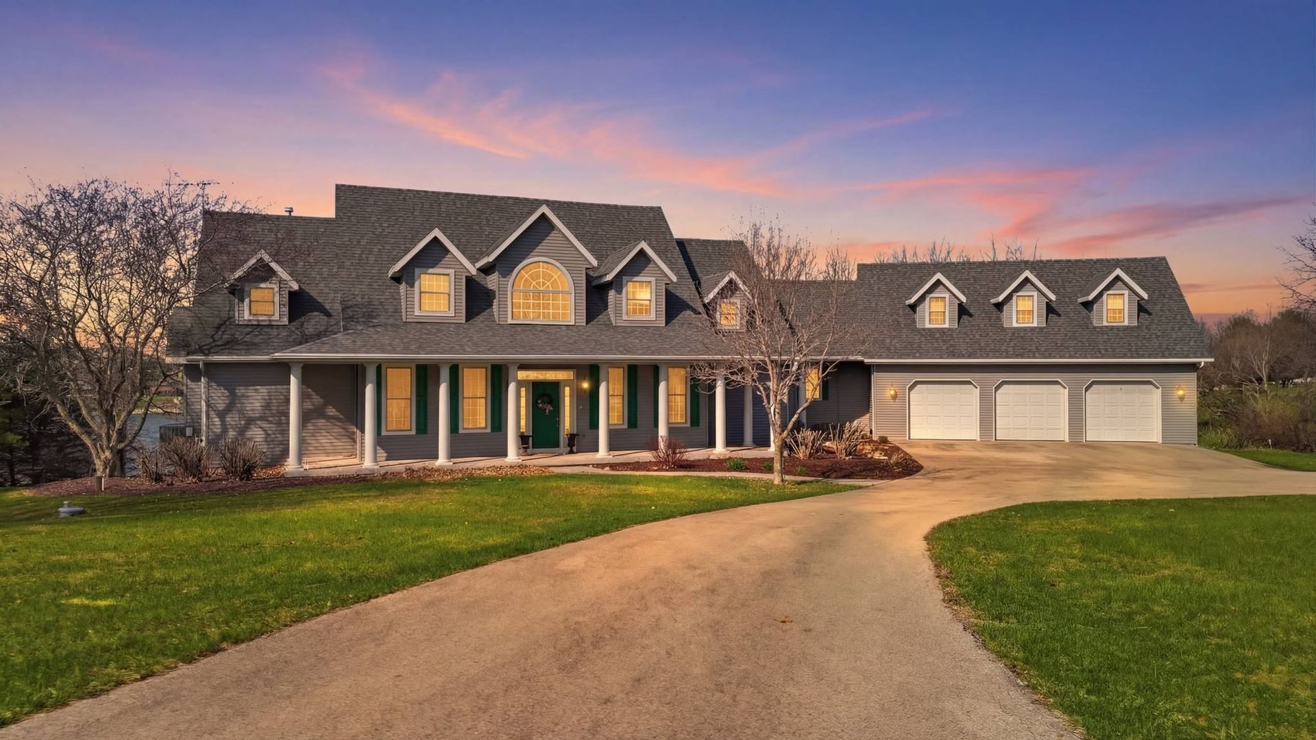 Twilight presentation of a home with dormer windows and a long front porch