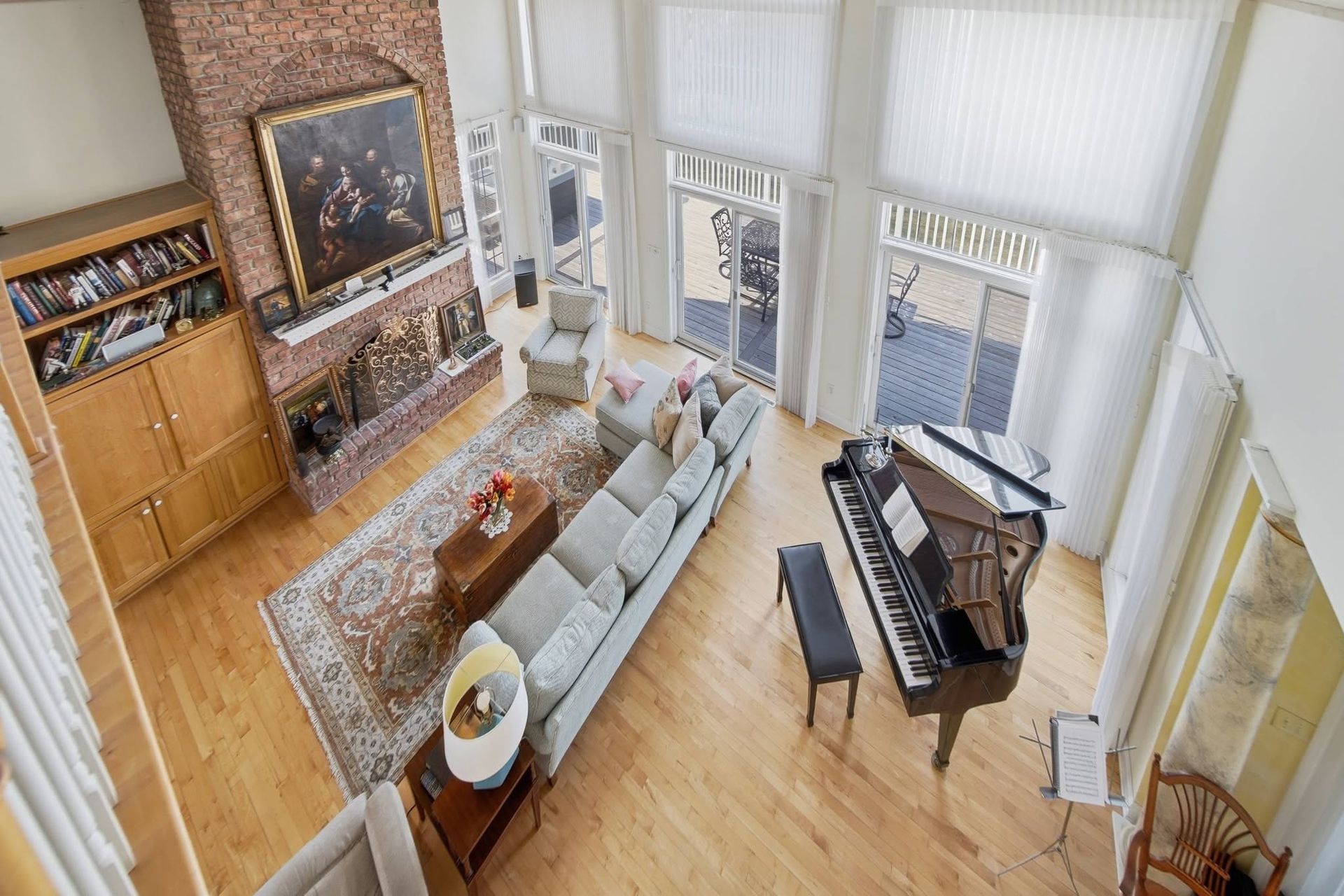 Living room viewed from above, with a fireplace, piano and tall windows