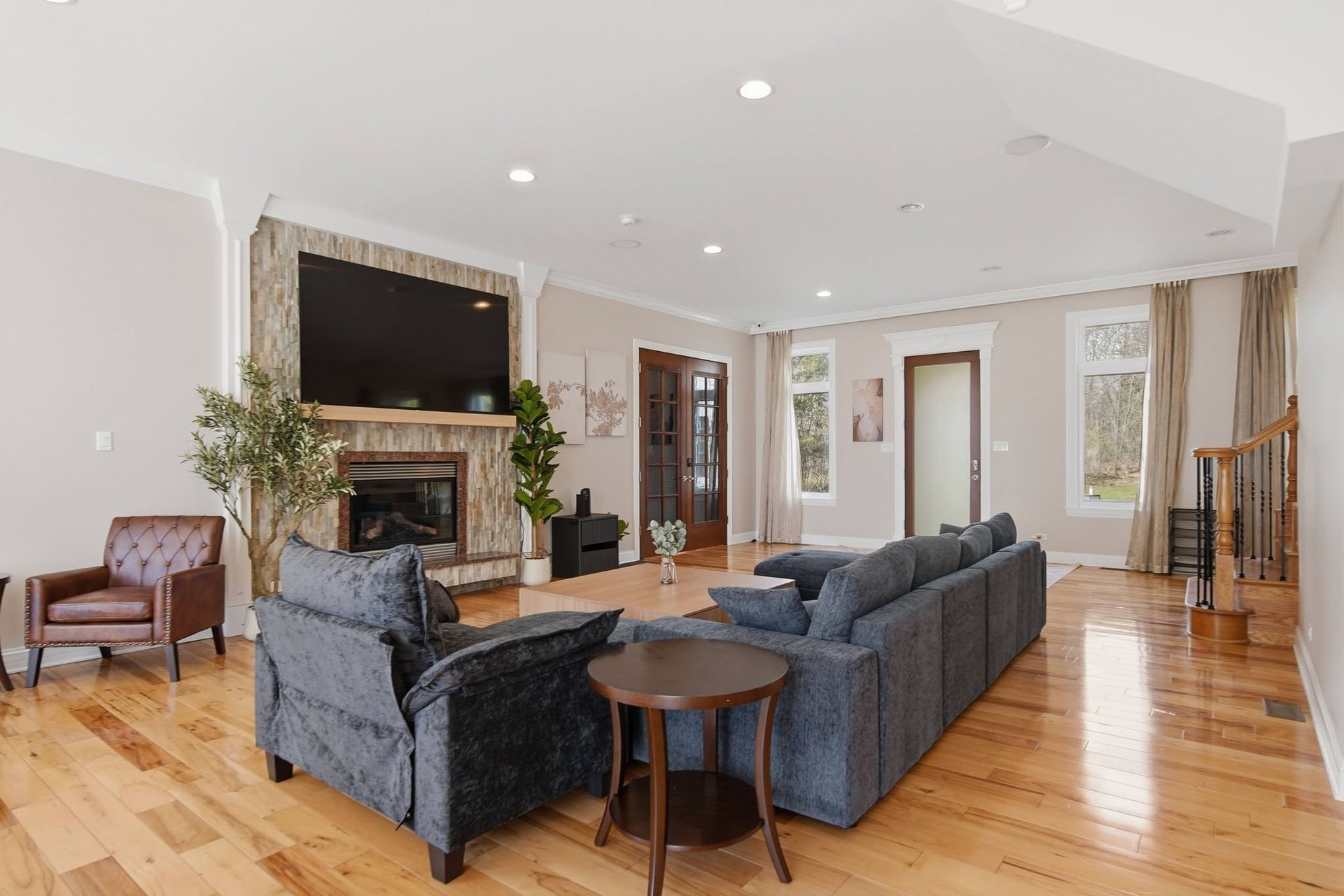Living room with dark sectional seating and a stone fireplace