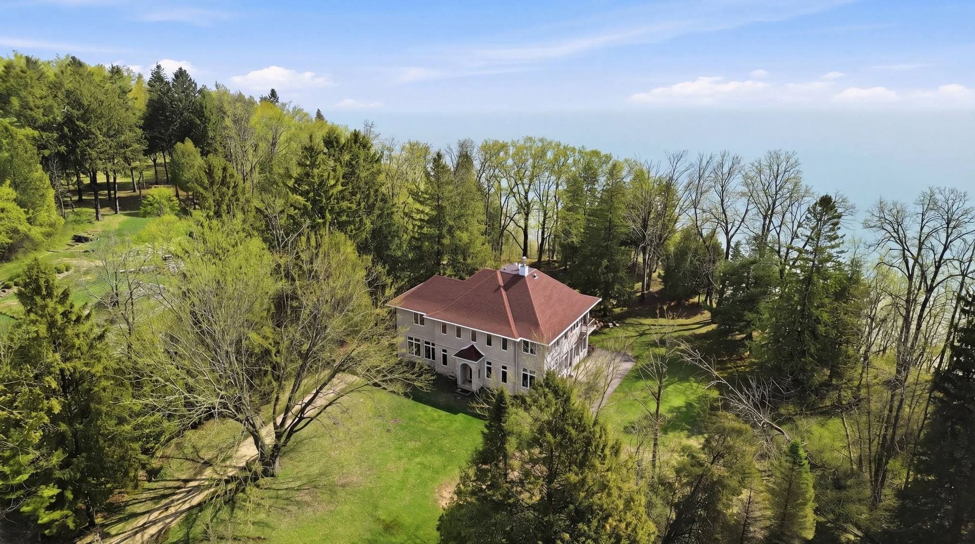 Aerial drone view of a home among trees near the water