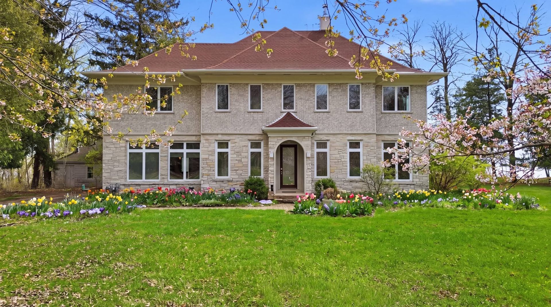 Two-story light-colored home with a central entrance and spring lawn