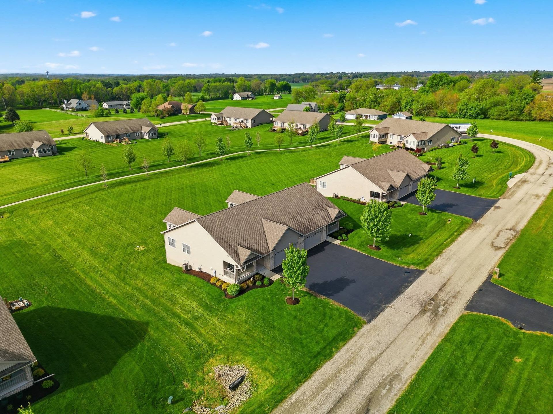 Aerial drone view of homes along a curved street beside open fields