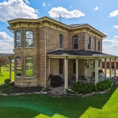 Two-story brick home with tall windows and a covered side porch