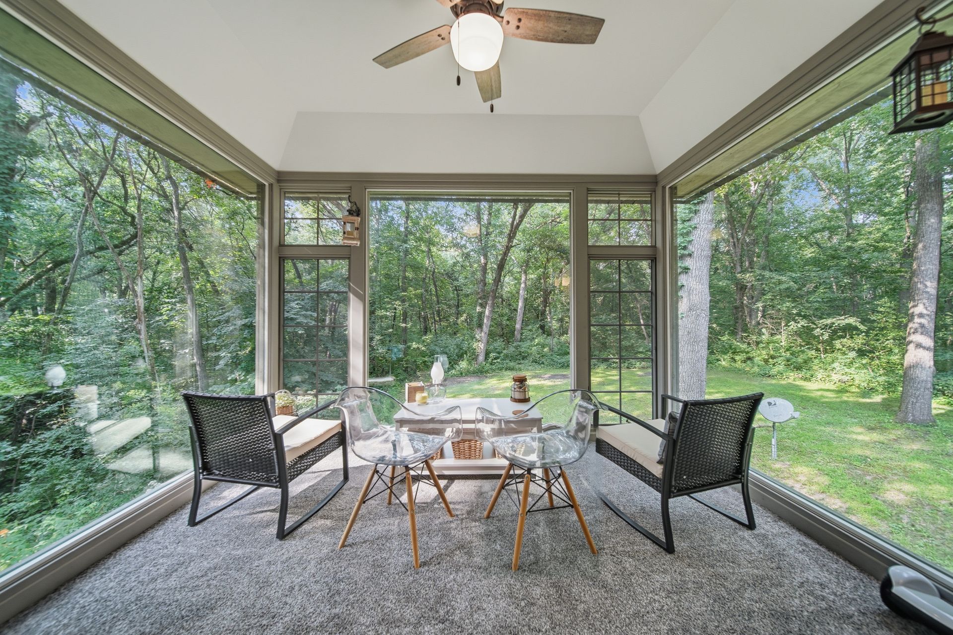 Screened porch with dining furniture overlooking a wooded yard