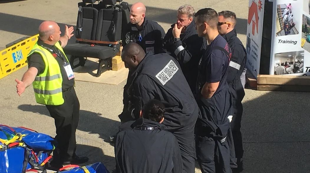Group of people in navy blue uniforms and yellow vest, with an injured person.