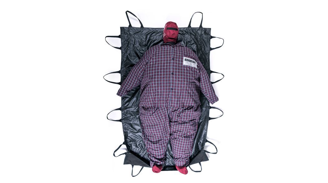 Person in plaid jumpsuit on a black stretcher with multiple handles.