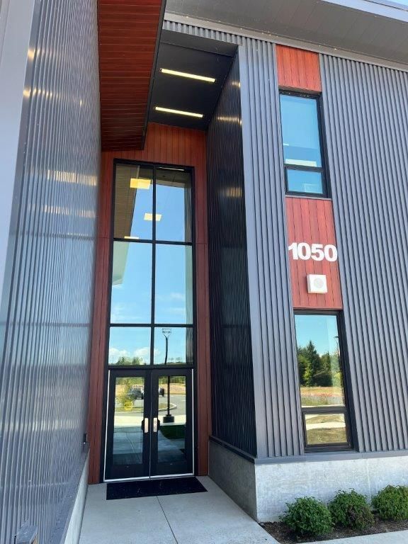 Modern building entrance with glass doors, vertical wood paneling, and the number 1050 beside the doorway